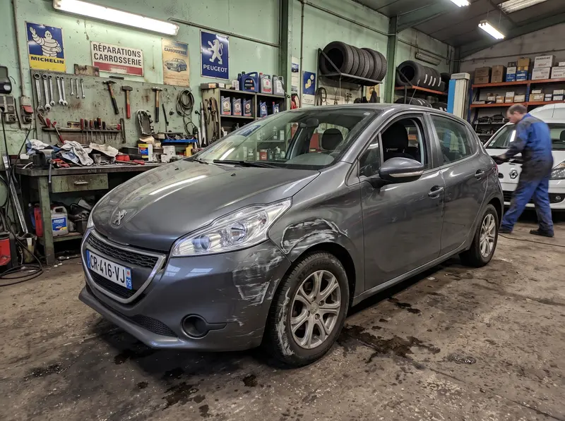 Aile avant d'une voiture grise rayée, avant réparation en atelier